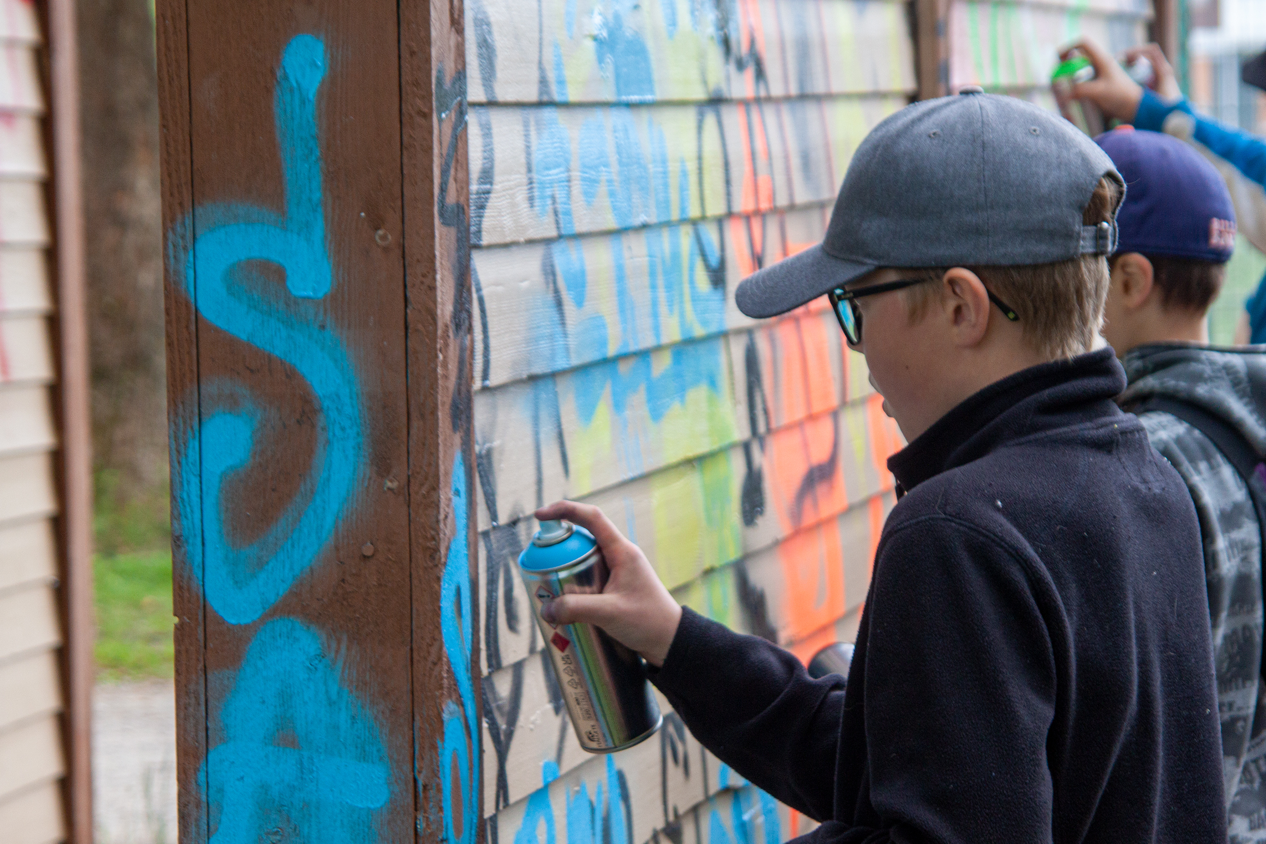 Nuori tekemässä graffitia spraykannu kädessään